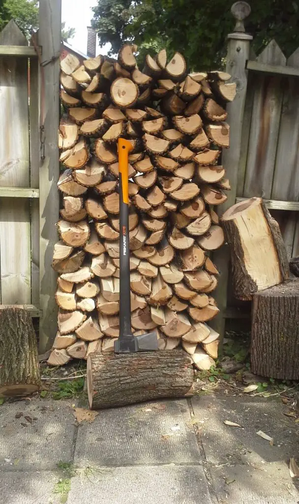 Fiskars X27 splitting axe leaning against firewood stack after field testing
